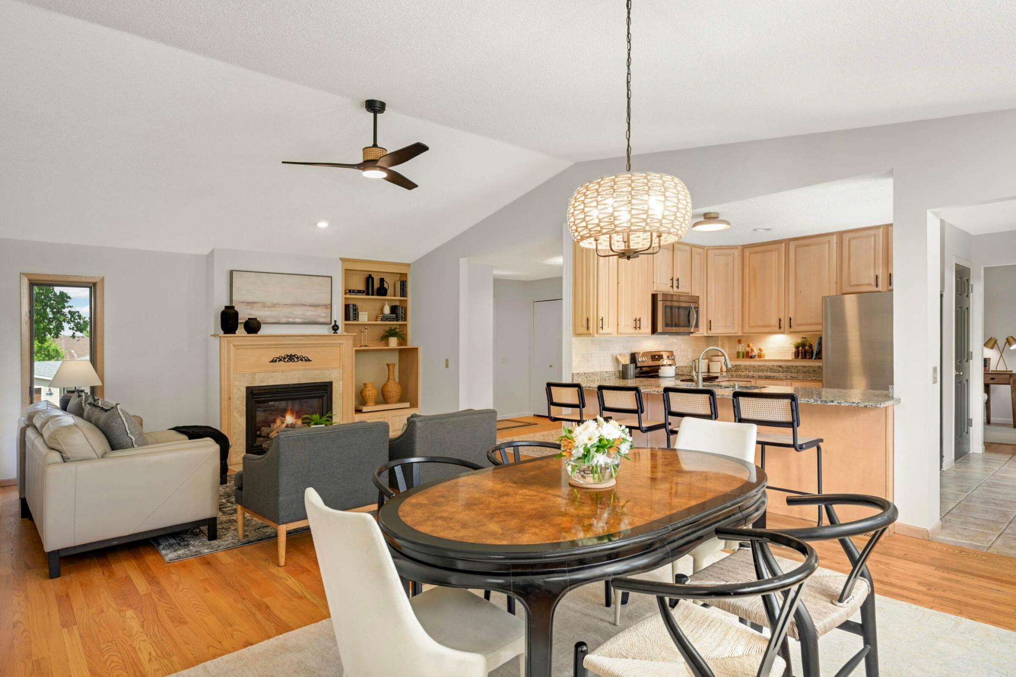 Open-concept living and dining area features beautiful light fixtures and a ceiling fan, and a seamless flow into the kitchen with a spacious breakfast bar.