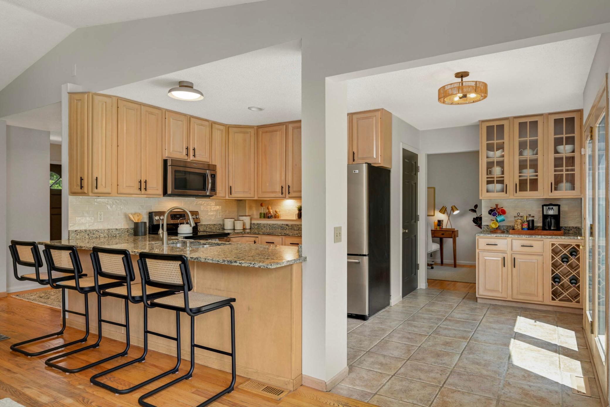 Stylish kitchen features natural wood cabinetry, granite countertops, stainless steel appliances, and a modern tile backsplash for a contemporary touch.