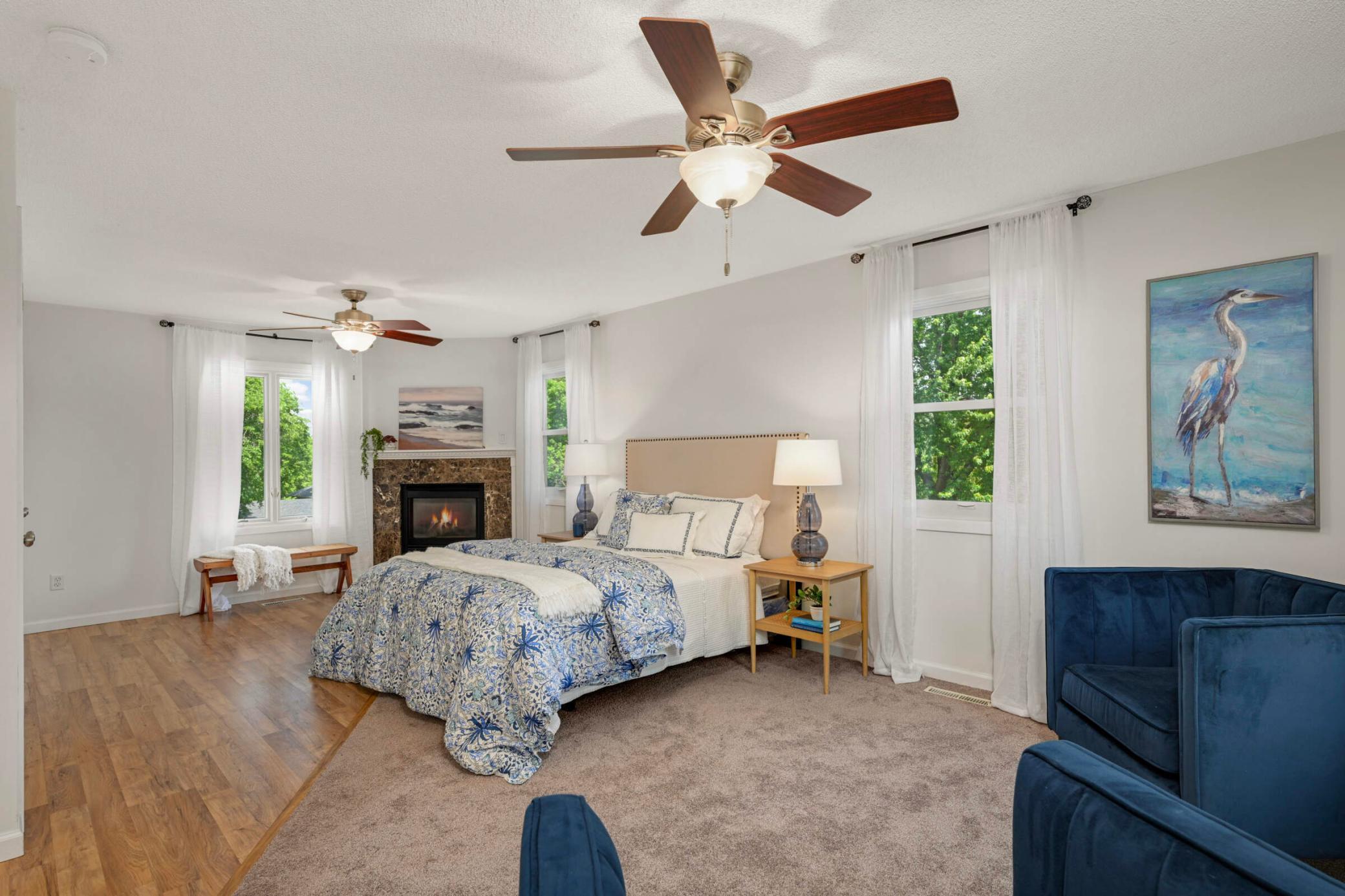 The primary bedroom offers abundant space for a sitting area and features a cozy fireplace and multiple windows for natural light.