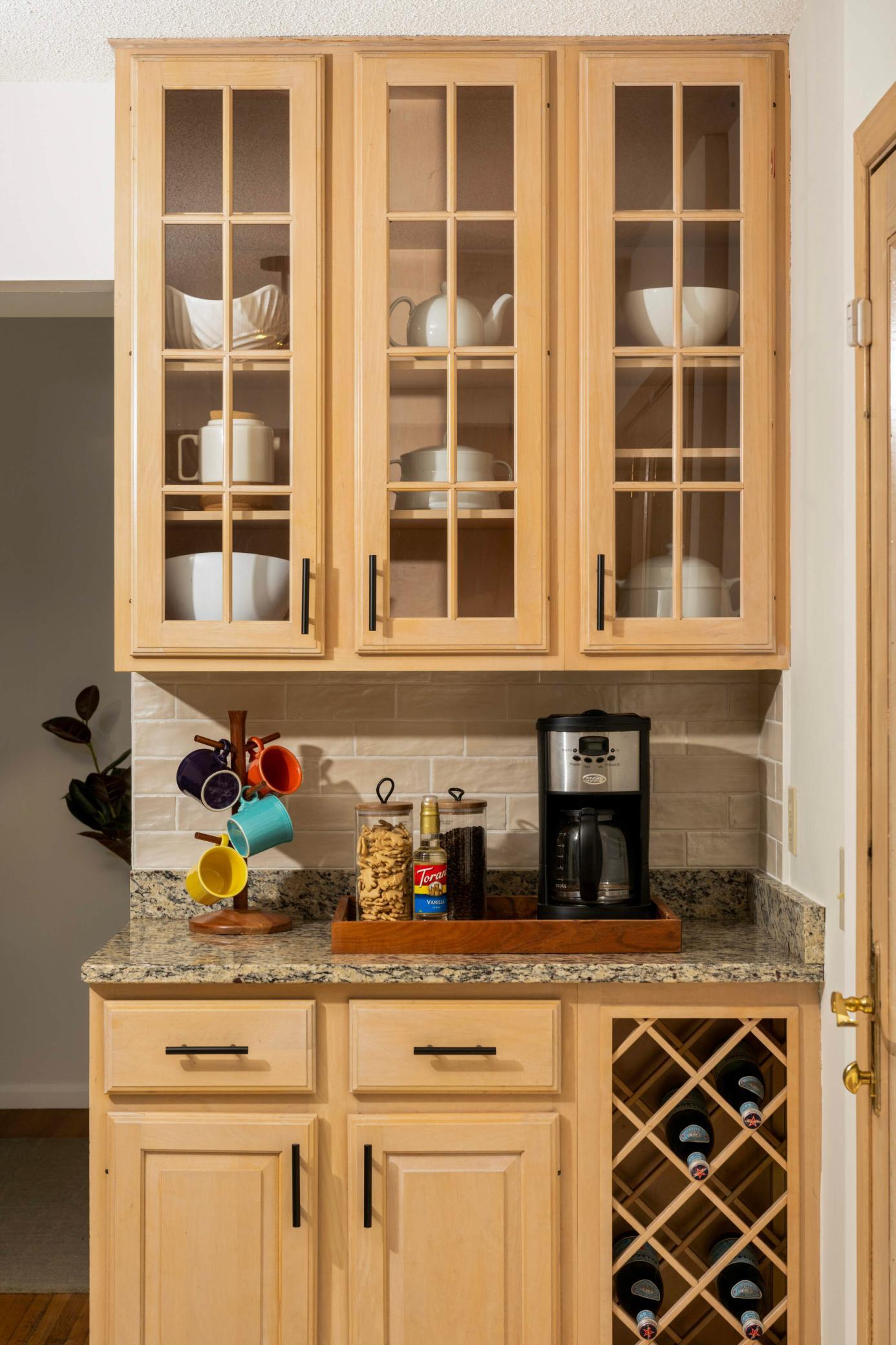Convenient coffee and charging station with glass front cabinetry and wine storage.