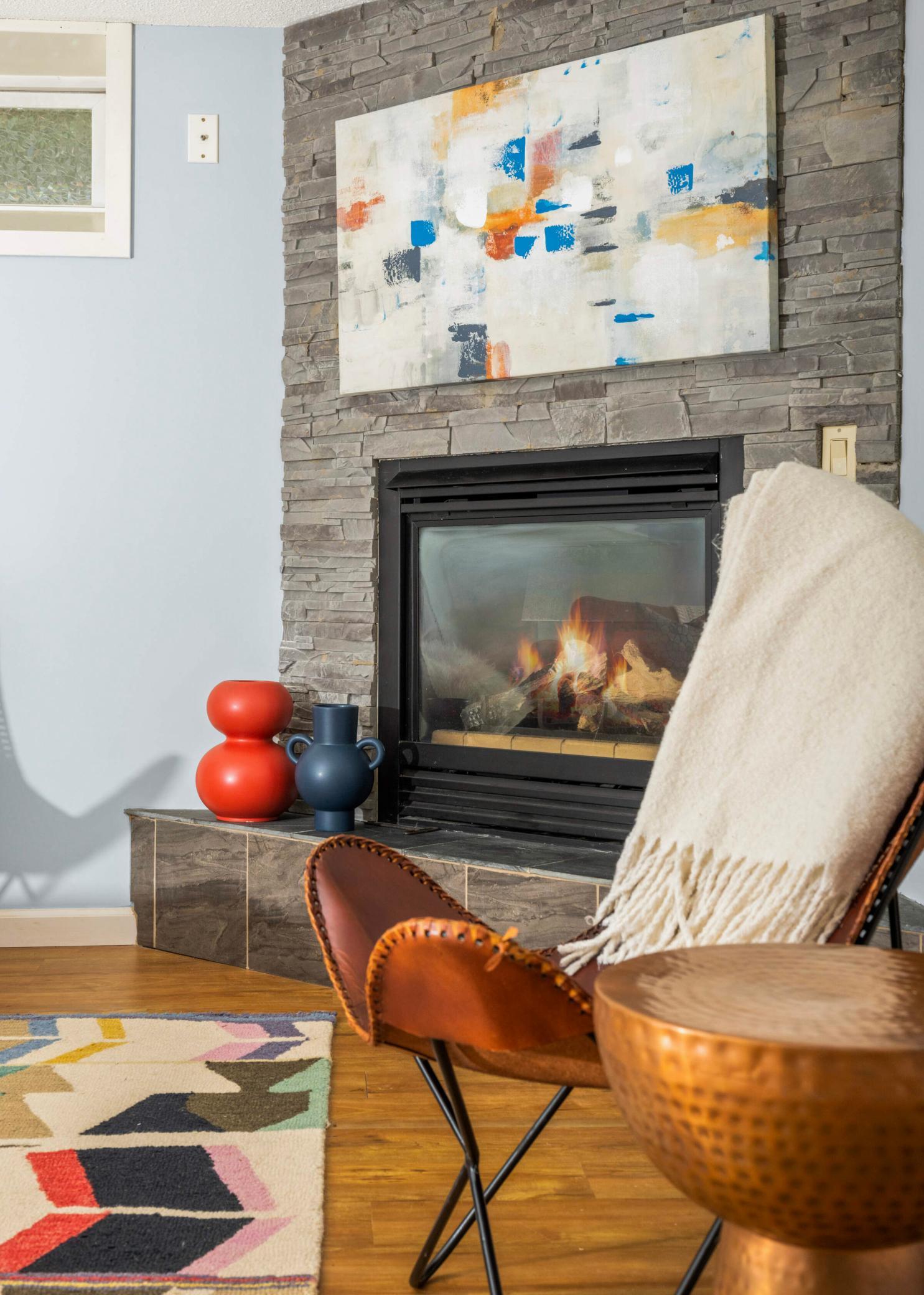 Gas fireplace features a stacked stone surround and raised hearth.