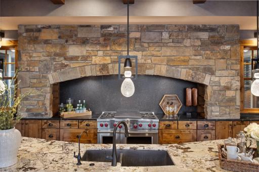 Featuring updated light fixtures, wood beams and soap stone perimeter counters. The 48â Wolf gas range with double ovens and range hood features a custom stone surround and honed granite backsplash