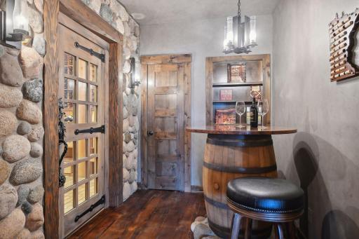 The tasting room and custom door with designer hardware and lock. There is a dedicated HVAC and humidity control for wine cellar behind cabinet door
