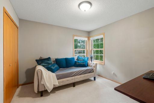 Bedroom two, located on the upper level, features soft carpeting, a generously sized closet, and windows offering views of both the side and rear of the home. Conveniently situated just steps from the shared full bathroom.