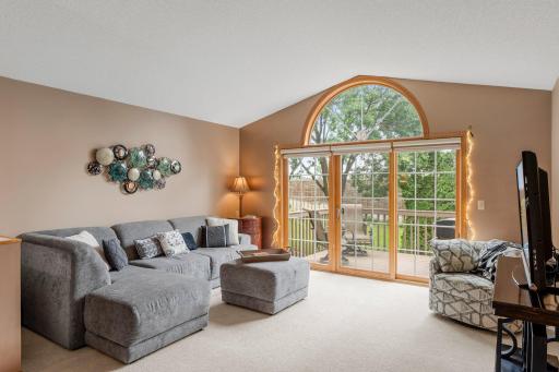 The spacious living room offers a warm and inviting atmosphere with carpeting and a vaulted 10-foot ceiling that enhances the open feel of the space.