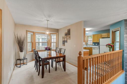 Adjacent to the kitchen, the dining room features soft carpeting, a stunning custom chandelier, and a beautiful bay window that floods the space with natural light.