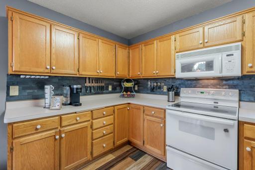 The kitchen showcases rich, multi-toned wood flooring and a stylish stone tile backsplash—both completed in 2023—adding warmth and a modern touch to the space.