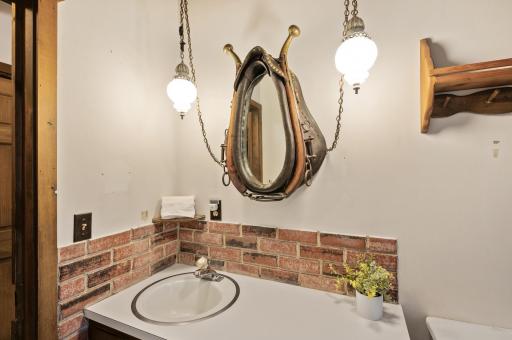 This bathroom radiates rustic charm, featuring a horse collar mirror and lighting accents.
