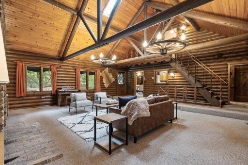 The living room offers soaring vaulted ceilings with exposed beams, skylights, and rustic details throughout including wagon wheel lighting and lantern fixtures.