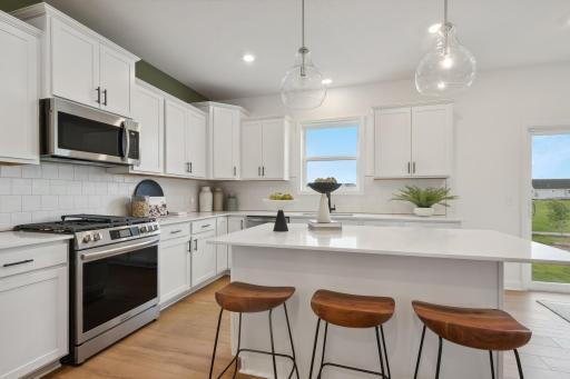 (Photo of a decorated model, actual homes finishes will vary) This thoughtfully-designed gourmet kitchen layout features granite countertops, stainless appliances, and a gas cooktop.