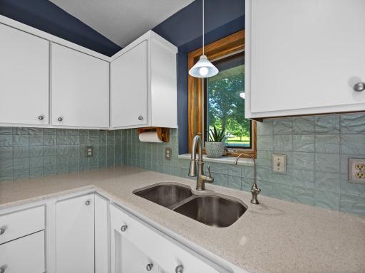 The kitchen features hard surface countertops and a stylish backsplash.