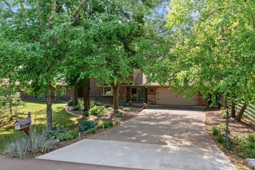 This home includes a concrete driveway and multiple mature trees that offer shade and privacy.