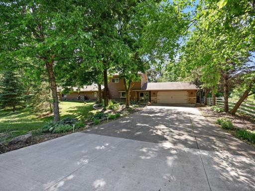 This home includes a concrete driveway and multiple mature trees that offer shade and privacy.
