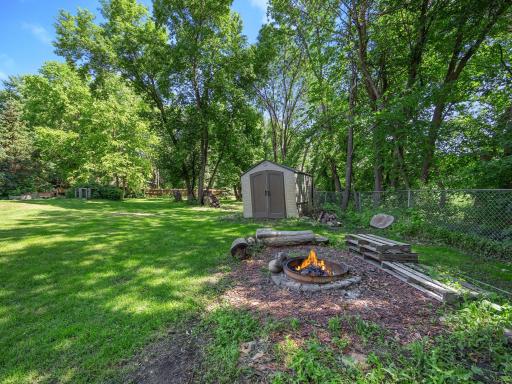The fenced in backyard includes a fire pit and a storage shed.