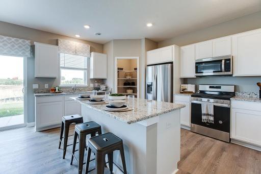 A kitchen built to perform - complete with an oversized island, pantry closet, stainless appliance package including a vented microhood and gas range, and enough space throughout for the family chef to roam about! (Photo of model, colors are similar)