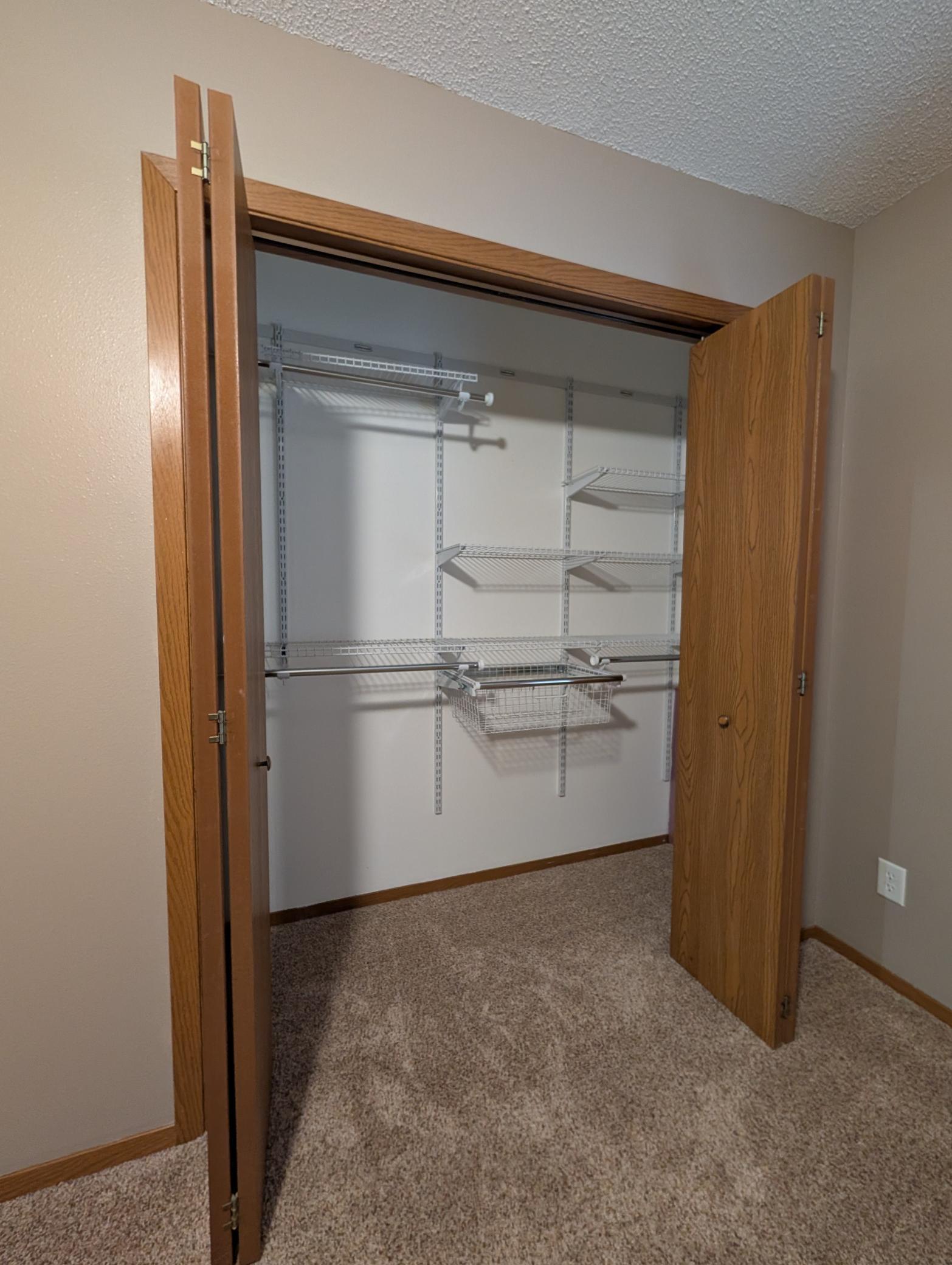 Spacious closet in primary bedroom boasts organizer racks, shelves & drawer combination.