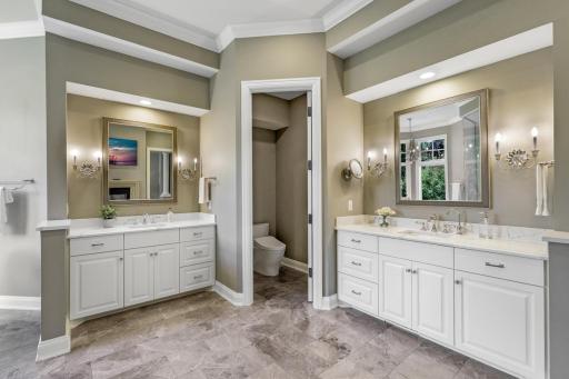 The complete remodel of the primary ensuite bathroom in 2021 showcases modern finishes, a walk-in steam shower with independently controlled shower heads, dual vanities, a two-sided gas fireplace, and a separate water closet.