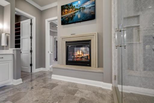 The complete remodel of the primary ensuite bathroom in 2021 showcases modern finishes, a walk-in steam shower with independently controlled shower heads, dual vanities, a two-sided gas fireplace, and a separate water closet.