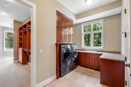 The perfectly sized, main-level laundry room features a side-by-side configuration, a wash sink, and plenty of counter and cabinet storage space.
