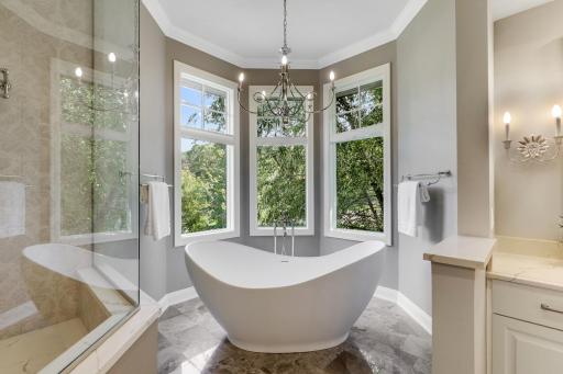 The complete remodel of the primary ensuite bathroom in 2021 showcases modern finishes, a walk-in steam shower with independently controlled shower heads, dual vanities, a two-sided gas fireplace, and a separate water closet.