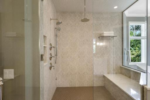The complete remodel of the primary ensuite bathroom in 2021 showcases modern finishes, a walk-in steam shower with independently controlled shower heads, dual vanities, a two-sided gas fireplace, and a separate water closet.