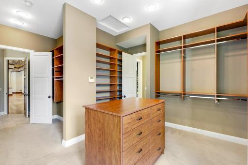 The ensuite walk-in closet boasts ample overhead lighting, natural light from a bank of windows, custom shelving and hanging racks throughout. It connects through to the main-floor laundry room for easy access, and for quiet exits.