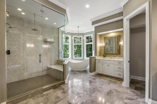 The complete remodel of the primary ensuite bathroom in 2021 showcases modern finishes, a walk-in steam shower with independently controlled shower heads, dual vanities, a two-sided gas fireplace, and a separate water closet.