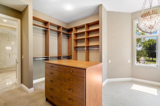The ensuite walk-in closet boasts ample overhead lighting, natural light from a bank of windows, custom shelving and hanging racks throughout. It connects through to the main-floor laundry room for easy access, and for quiet exits.