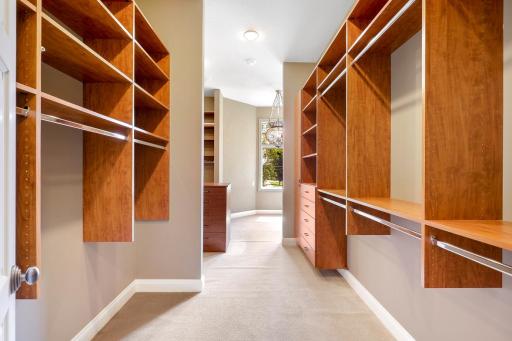 The ensuite walk-in closet boasts ample overhead lighting, natural light from a bank of windows, custom shelving and hanging racks throughout. It connects through to the main-floor laundry room for easy access, and for quiet exits.