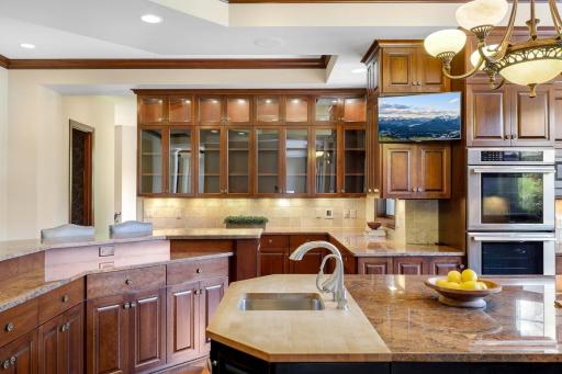 The chef’s kitchen features large windows, a double wall oven, 5-burner gas cooktop, built in microwave, generously sized refrigerator, abundant cabinet storage, 2 center islands and granite countertops.