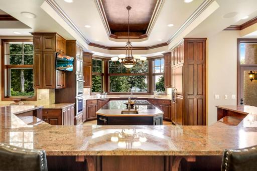 The chef’s kitchen features large windows, a double wall oven, 5-burner gas cooktop, built in microwave, generously sized refrigerator, abundant cabinet storage, 2 center islands and granite countertops.
