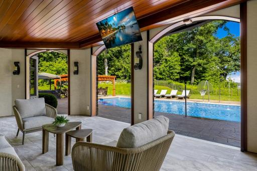 Just off the pool is a patio that was converted by the current owners to an indoor/outdoor cabana space, featuring motorized Phantom screens, a retractable TV and an outdoor gas fireplace.