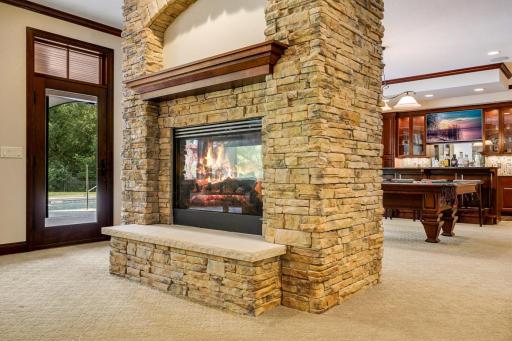 A cozy, double-sided fireplace separates the billiard room from the theater room.