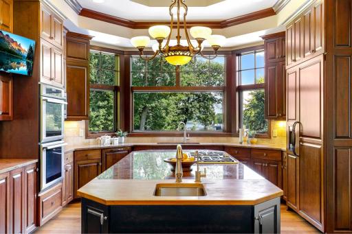 The chef’s kitchen features large windows, a double wall oven, 5-burner gas cooktop, built in microwave, generously sized refrigerator, abundant cabinet storage, 2 center islands and granite countertops.