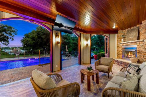 Just off the pool is a patio that was converted by the current owners to an indoor/outdoor cabana space, featuring motorized Phantom screens, a retractable TV and an outdoor gas fireplace.