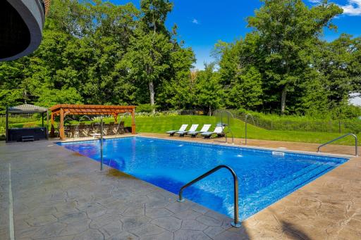 Stamped concrete encircles the pool area, and the private, mostly flat and fully fenced back yard provides ample space for yard games and outdoor relaxation.