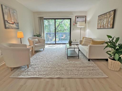 Spacious living room with newer flooring opens to a balcony deck