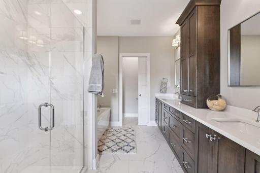 Spa-like primary bath with electric heated floors, dual sinks and vanity areas, large soaker tub, and separate walk-in shower.