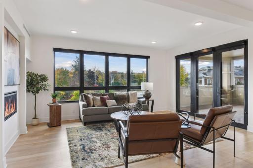 Sun-filled living room offers cozy gas fireplace, engineered oak floors, and access to the covered balcony.