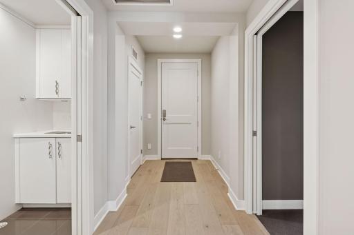 View of front door with laundry room to left and guest bedroom suite to the right