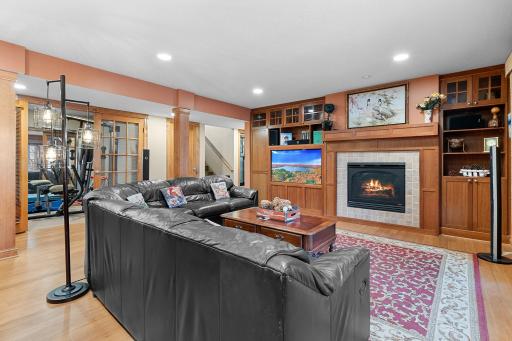 Lower-level recreation room with fireplace, cherry media cabinets. Ceiling speakers connect to media cabinet.