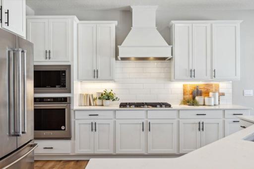 Stunning wood hood, gas cooktop, built in wall oven and microwave. Photo of a model home, color & options will vary.