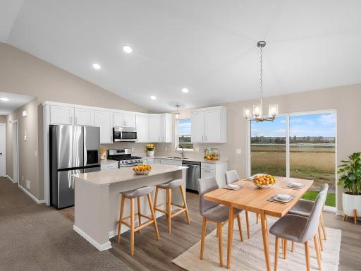 Kitchen and dining room offer back yard views. Photo of a different home with similar plan & finishes virtually staged.