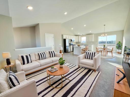 Vaulted ceiling in the great room, kitchen, and dining room. Photo of a different home with similar plan & finishes virtually staged.