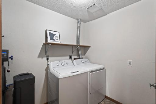The laundry room includes a a new washer and dryer set that were installed in 2023. The new Culligan water softener was installed in 2022. Just behind the door you will find built-in shelving for additional storage space.