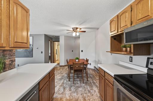 In this view from the kitchen looking down the hall you will see the second bedroom and full bathroom. There is a ceiling fan with a light in the dining room which provides a gentle breeze and air circulation throughout the home.