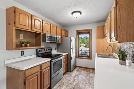 In this reverse view of the kitchen notice the undercabinet lighting above the sink and the built-in microwave above the stove which is a great space saver.