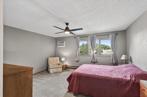The primary bedroom is generously sized and includes a newer ceiling fan with a light, newer carpet, new Anderson windows, and a newer AC unit.