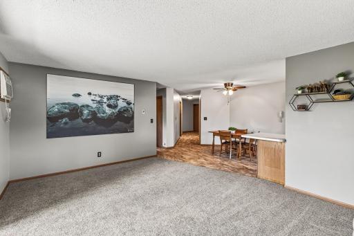 Here is a reverse view from the living room into the dining room. The center hall leads to the main entry, laundry room, and primary suite. In the hall to the left you will find the second bedroom and a full bathroom.