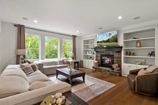 The expansive living room offers a warm and inviting atmosphere, highlighted by a stunning stone gas fireplace and custom built-insâperfectly combining comfort, style, and functional elegance.